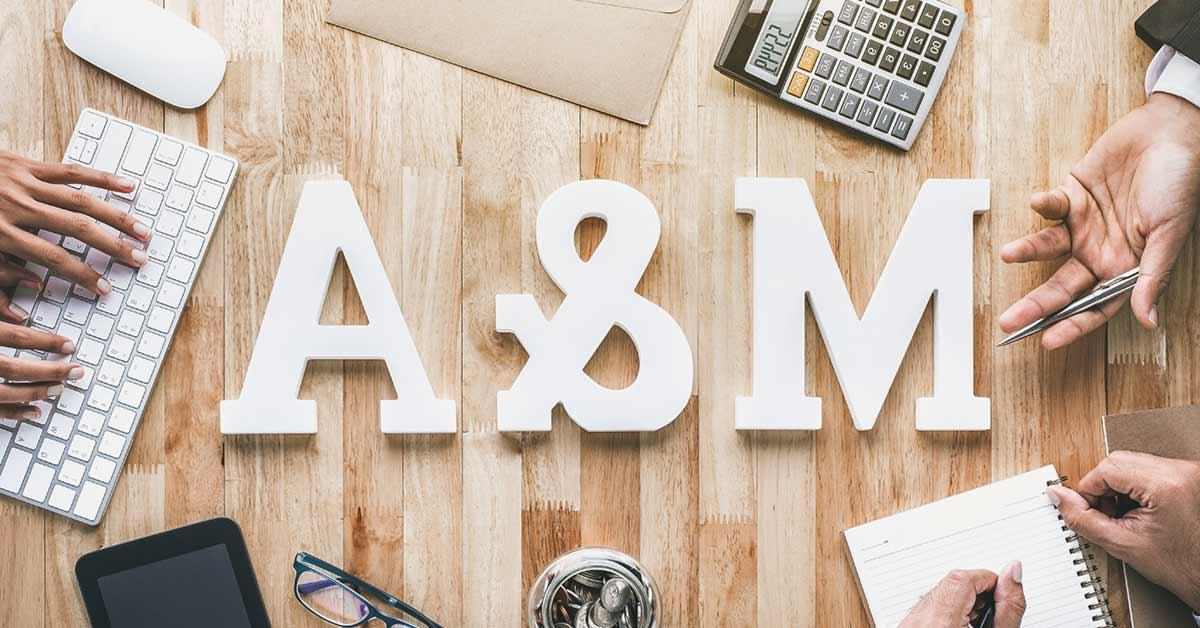 white block letters m&a on a wooden desk that stand for merger and acquisition